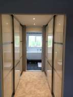 Wardrobes on both sides of a corridor between the bedroom and ensuite with door open