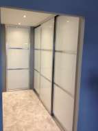 Showing the wardrobes doors on the right side of the corridor, which are soft white glass with polished silver frames