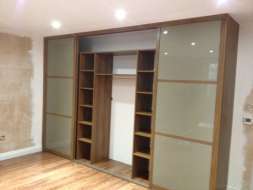 Light brown glass wardrobes doors with a walnut frame with middle doors open (from the right view)